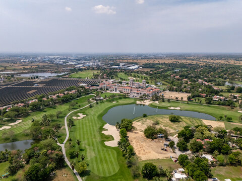 Ahmedabad, India - 21 March 2026: Aerial view of Kalhaar Blues and Greens Golf Club featuring lush green fairways, a central lake, and surrounding landscape.