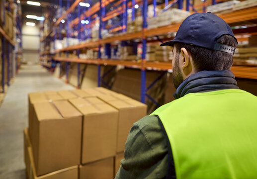 Warehouse worker moves pallet boxes along shelves. Logistics delivery in a busy storage facility, inventory prepared for shipment and timely distribution. Concept of modern warehouse logistics.