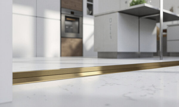 Vacuum floor inlet matte brass trim installed in a minimalist modern kitchen featuring clean white surfaces