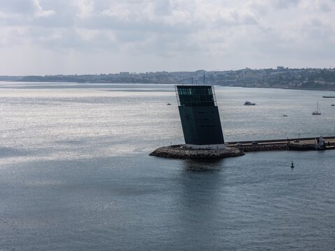 Alges, Lisbon, Portugal - 25 July 2026: Aerial view of the Torre VTS de Alges, a modern maritime traffic control tower on a breakwater in the Tagus River with boats and coastline.