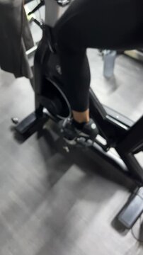 Woman adjusting stationary spinning bike seat in gym close up