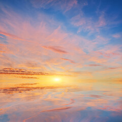 Fototapeta premium Beautiful golden sunset sky with pink clouds reflecting in the calm water surface.