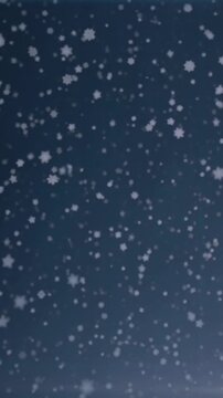 Snowflakes falling against evening sky, vertical slow motion