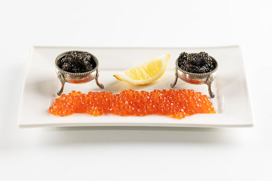 Red and black caviar on white platter. Natural omega. Slice of lemon next to caviar. Isolated object. An exquisite snack. Luxury gourmet food. Natural omega. Isolated object