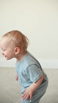 Adorable one year old toddler girl smiling while dancing and standing independently in a bright modern home with natural daylight.