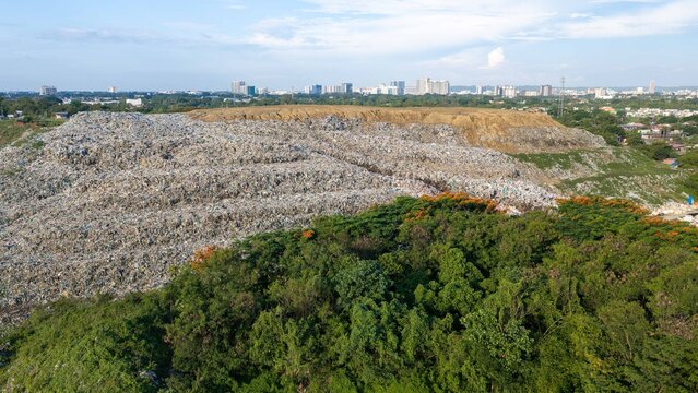 Iloilo City, Western Visayas, Philippines - 25 July 2026: Aerial view of Iloilo City Landfill with large waste piles, surrounding lush greenery, and the distant city skyline.