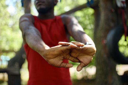 Black young adult man stretching hands before outdoor workout, preparing body for exercise and fitness routine. Useful for wellness, training, active lifestyle, injury prevention marketing