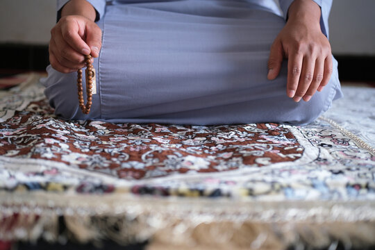 Close-up of hands reciting dhikr using prayer beads. Hands reciting dhikr. A man reciting dhikr while holding prayer beads. A Muslim's worship activity.
