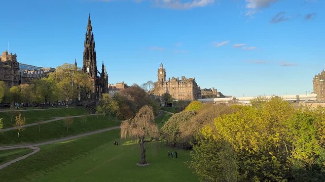 Static panoramic view of Princes Street Gardens in Edinburgh, Scotland, featuring the iconic Scott Monument with Edinburgh Castle visible in the background.