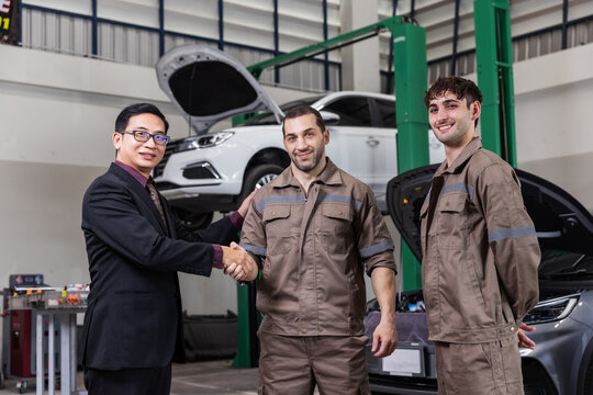 Customer Shaking Hands with Professional EV Service Team in Modern Electric Vehicle Repair Workshop