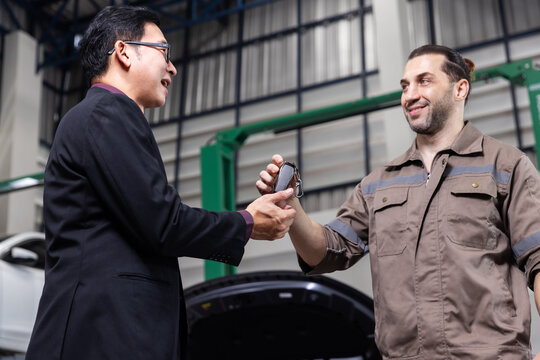 Professional EV technician handing over car keys to a satisfied customer after completing electric vehicle maintenance in a modern service workshop.