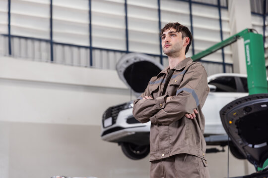 Confident EV Service Engineer Standing in Modern Electric Vehicle Repair Workshop with High Voltage Battery Expertise