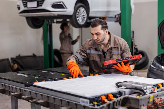 EV Technician Using Professional Battery Diagnostic Tablet During Electric Vehicle Maintenance