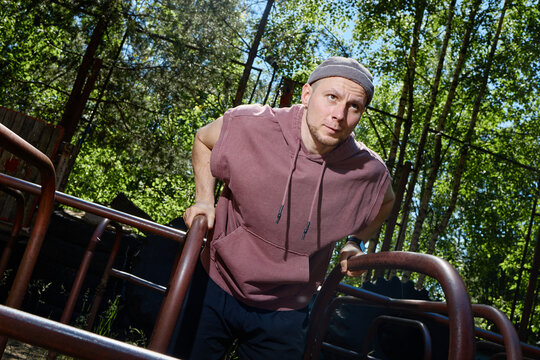 Caucasian young adult man exercising on parallel bars in outdoor fitness park, building upper body strength and endurance. Useful for sports training, wellness, active lifestyle marketing