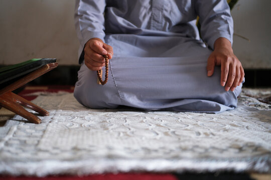 Close-up of hands reciting dhikr using prayer beads with a blurred background. Hands reciting dhikr. A man reciting dhikr while holding a prayer bead. Front view photo
