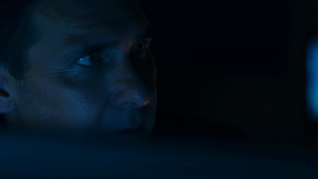 Extreme closeup of male eyes and upper face shifting gaze in low key blue light, with focused expression, subtle tension, dark contrast, and moody investigative atmosphere