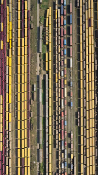 Chattogram, Chittagong Division, Bangladesh - 26 February 2025: Aerial view of the extensive rail yard with numerous rows of yellow and maroon freight train cars parked on parallel tracks.