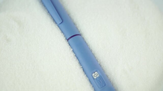 blue insulin pen Ozempic lying in sugar crystals, conceptual photo representing diabetes management, blood sugar control, and metabolic health, healthcare and pharmacy industry.