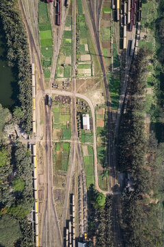 Chattogram, Chittagong Division, Bangladesh - 26 February 2025: Aerial view of the Rail Yard with multiple tracks, freight trains, small agricultural plots, and surrounding lush vegetation.