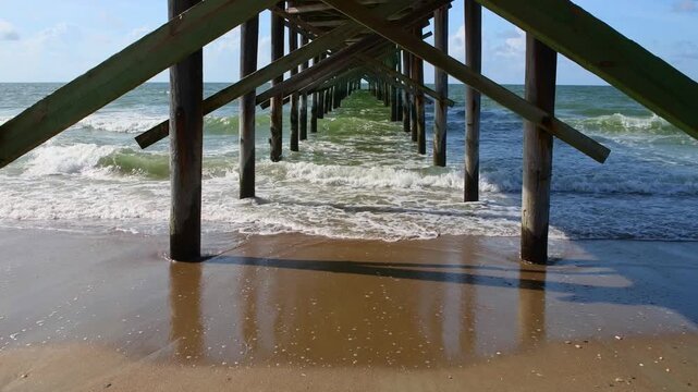 Ocean waves breaking under a wooden pier