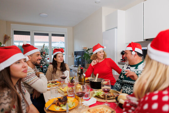 Family wearing santa hats celebrating christmas dinner