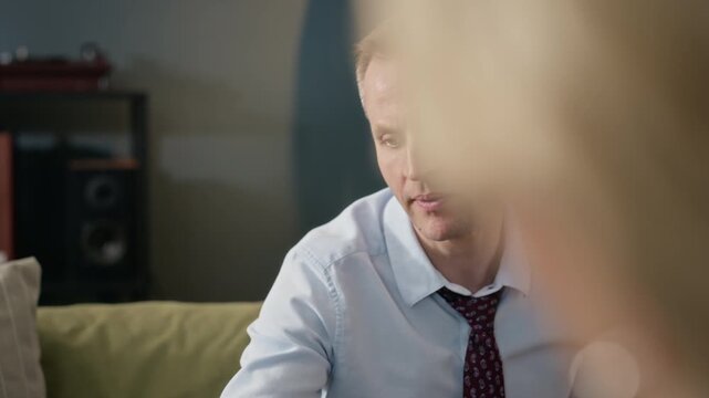 Middle-aged Caucasian man sitting on sofa, picking up inkblot test paper and talking to therapist during psychology session. Footage is ideal for mental health awareness campaigns