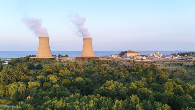 Frenchtown Township, Michigan, United States - 24 July 2026: Aerial view of Enrico Fermi II NPP with cooling towers emitting steam, situated on the shore of Lake Erie surrounded by lush green forest.