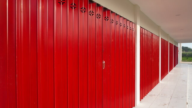 Side perspective features vibrant red folding metal gates along outdoor store corridor space