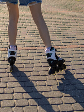Close up of teenage girl's feet wearing inline roller skates on a paved walkway during a summer outdoor activity. Concept of active lifestyle, movement, fitness and urban recreation.