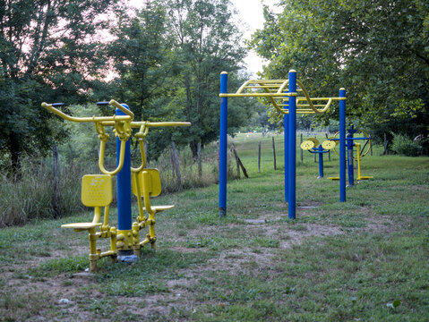 Gimnasio al aire libre en un parque entre la naturaleza donde se pueden observar las m&aacute;quinas de hacer ejercicio entre los &aacute;rboles.