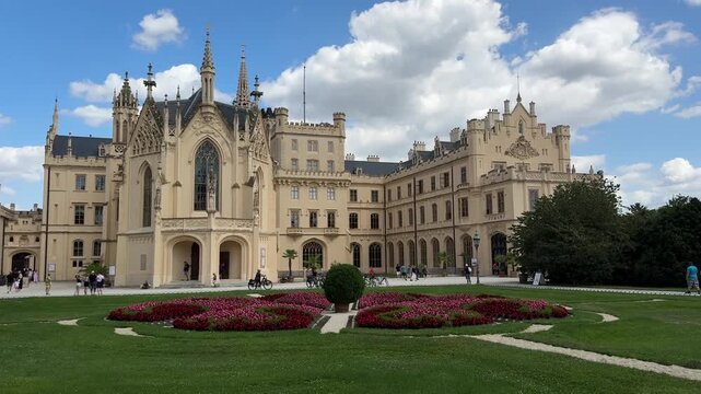 Visitors explore the Neo Gothic courtyard of Lednice Castle surrounded by formal gardens in the Czech Republic. Historic architecture, cultural heritage, sightseeing, tourism and European travel desti