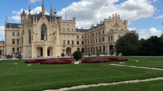 Visitors explore the Neo Gothic courtyard of Lednice Castle surrounded by formal gardens in the Czech Republic. Historic architecture, cultural heritage, sightseeing, tourism and European travel desti