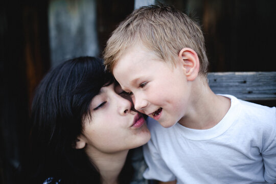Close up portrait of two young siblings sharing a playful and affectionate moment with smiling faces and cheek to cheek interaction