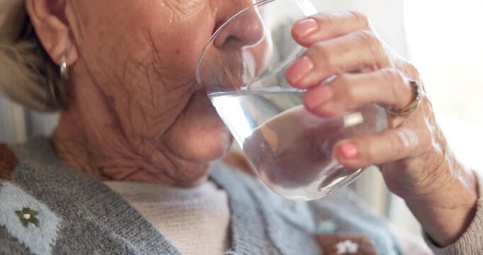 Old woman, drinking water and hand with glass in house, nutrition and digestion with liquid mineral. Retirement, wellness and elderly person with beverage for hydration, thirsty and detox in home