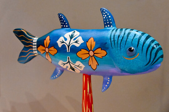 handcrafted wooden fish sculptures on metal stands close up, colorful painted fish figurines on display, rustic coastal decor craft, traditional brazilian wooden handicraft with copy space