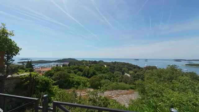 View of the Adriatic coast with lush greenery and a metal railing overlooking the sea in Vrsar, Istria County, Croatia.