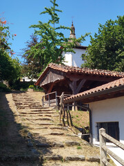 Fototapeta premium Escalinata rústica de piedra hacia casas tradicionales bajo árboles verdes en Zerain, Guipuzcoa, España