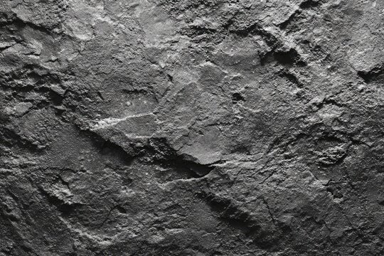 Close-up view of a rough, textured surface resembling a dark gray slate or stone