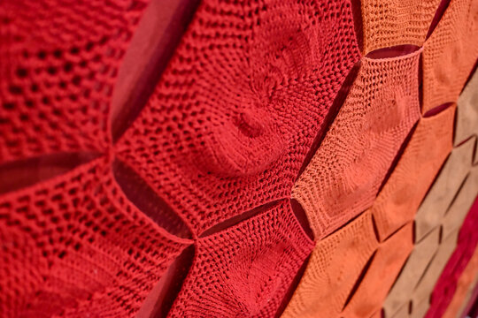 red crochet pattern background close up, handmade knitted fabric texture in warm gradient tones, detailed view of red and orange lacework handicraft, cozy wool textile pattern with copy space