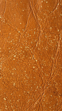 Macro texture of brown leather with craquelure effect and gold foil accents