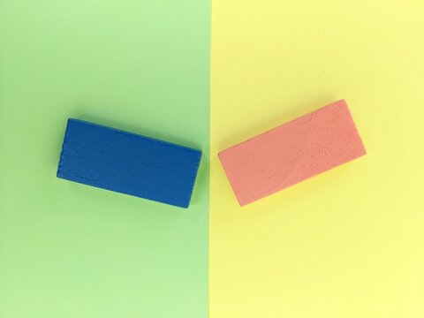 Blue and pink wooden blocks on pastel split background, emphasizing symmetry, contrast and everyday stationery design. Copy space for concept and design ideas