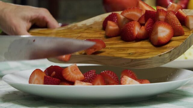 Closeup shot of knife moving diced strawberries onto plate