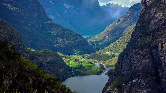 View of the lush green valley and fjord surrounded by steep mountains in Flam, Vestland, Norway.