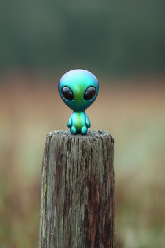 creature of ai, cute tiny green and blue alien with large black eyes sitting on a wooden post, charcoal, photorealistic