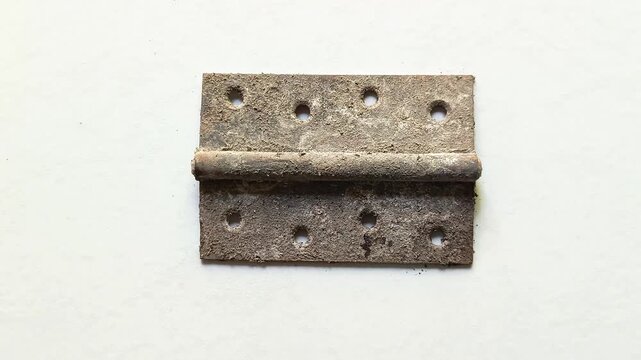 Old rusty weathered iron metal door hinge with screw holes isolated on clean white background