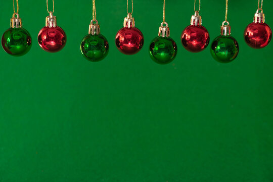 Hanging red and green Christmas balls on green background with space for text