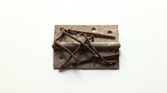 Old rusty weathered iron metal door hinge with bent rusty nails isolated on clean white background