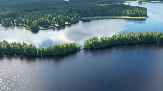 Aerial drone footage of Kyyn&auml;r&auml;nharju esker in Liesj&auml;rvi National Park, Finland. Narrow forested ridge separating serene lakes under a bright summer sky.