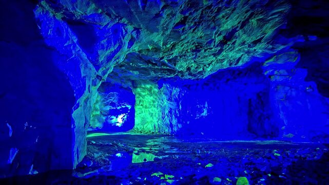 View of a cave interior illuminated with vibrant blue and green artificial lights in Flam, Vestland, Norway.