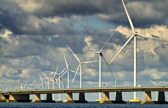 Ketelbrug bridge spanning water with wind turbines generating clean energy under dramatic clouds